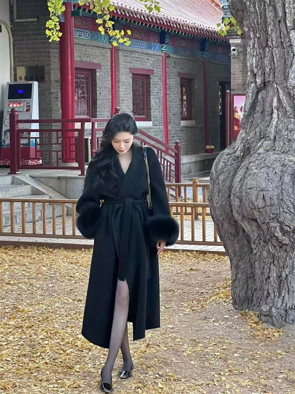 Model in a black premium coat photographed in a heritage courtyard setting.
